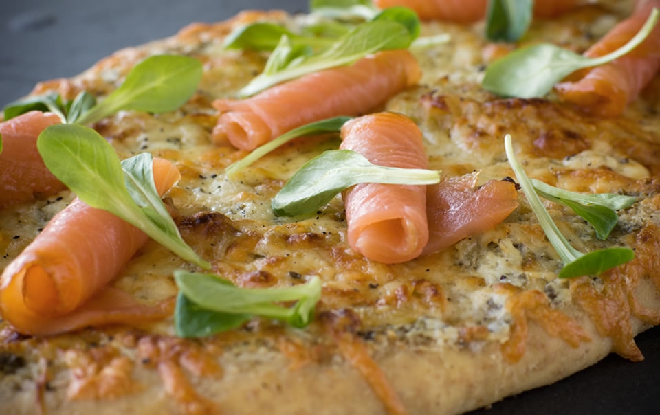 Pizza with smoked salmon, crème fraîche, herbs, garlic confit and onion compote